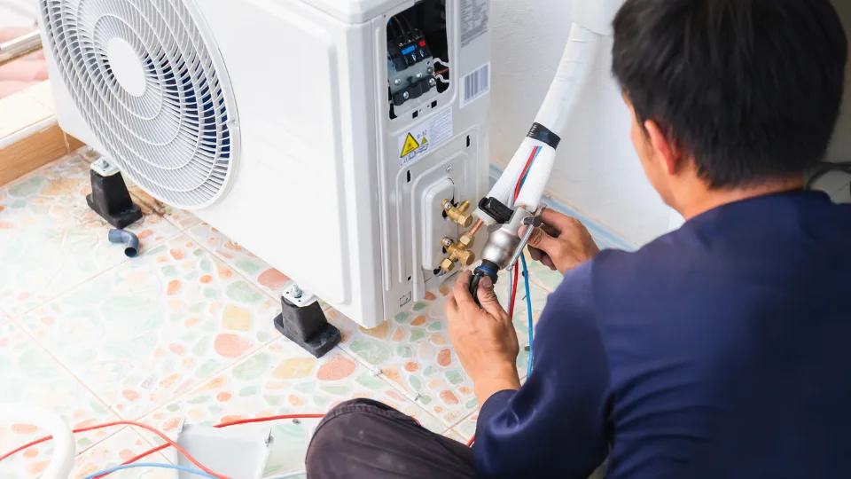 HVAC technician examining air conditioning system.