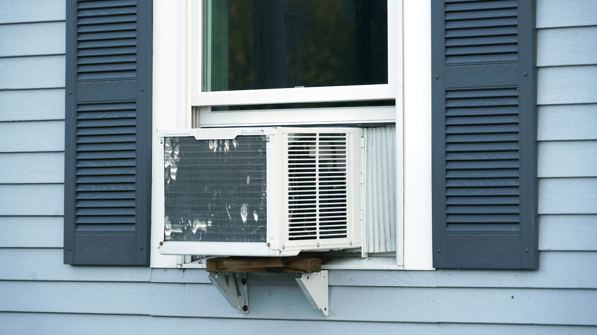 old window air conditioner hanging out of home window.