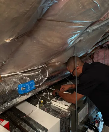 Jay Moody HVAC technician installing new ductwork and central heat pump in Worcester, MA home.