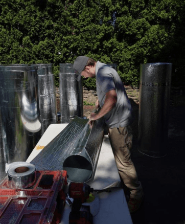 HVAC technician constructing ductwork in front of Worcester, Massachusetts home.