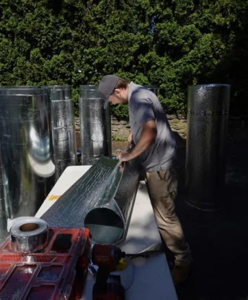HVAC technician constructing ductwork in front of Worcester, Massachusetts home.