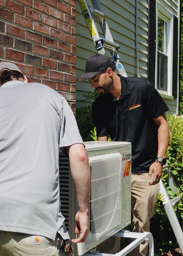 HVAC technicians installing outdoor mini-split condenser for Shirley, Massachusetts home,.
