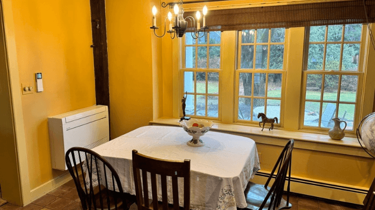 Floor-mounted Mitsubishi mini-split in yellow dining/kitchen area in Harvard, MA home.